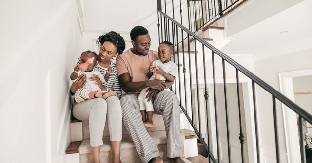 Family of four sits on stairs: parents hold children.